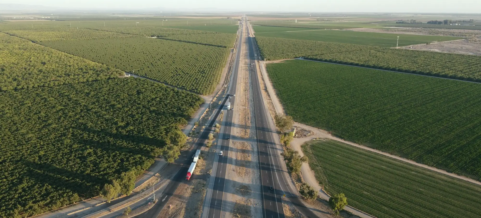 Trucks on a US interstate running between farm fields, seen from above